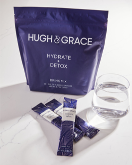 The Hydrate plus Detox set with individual packets stacked in front, and a glass of water.
